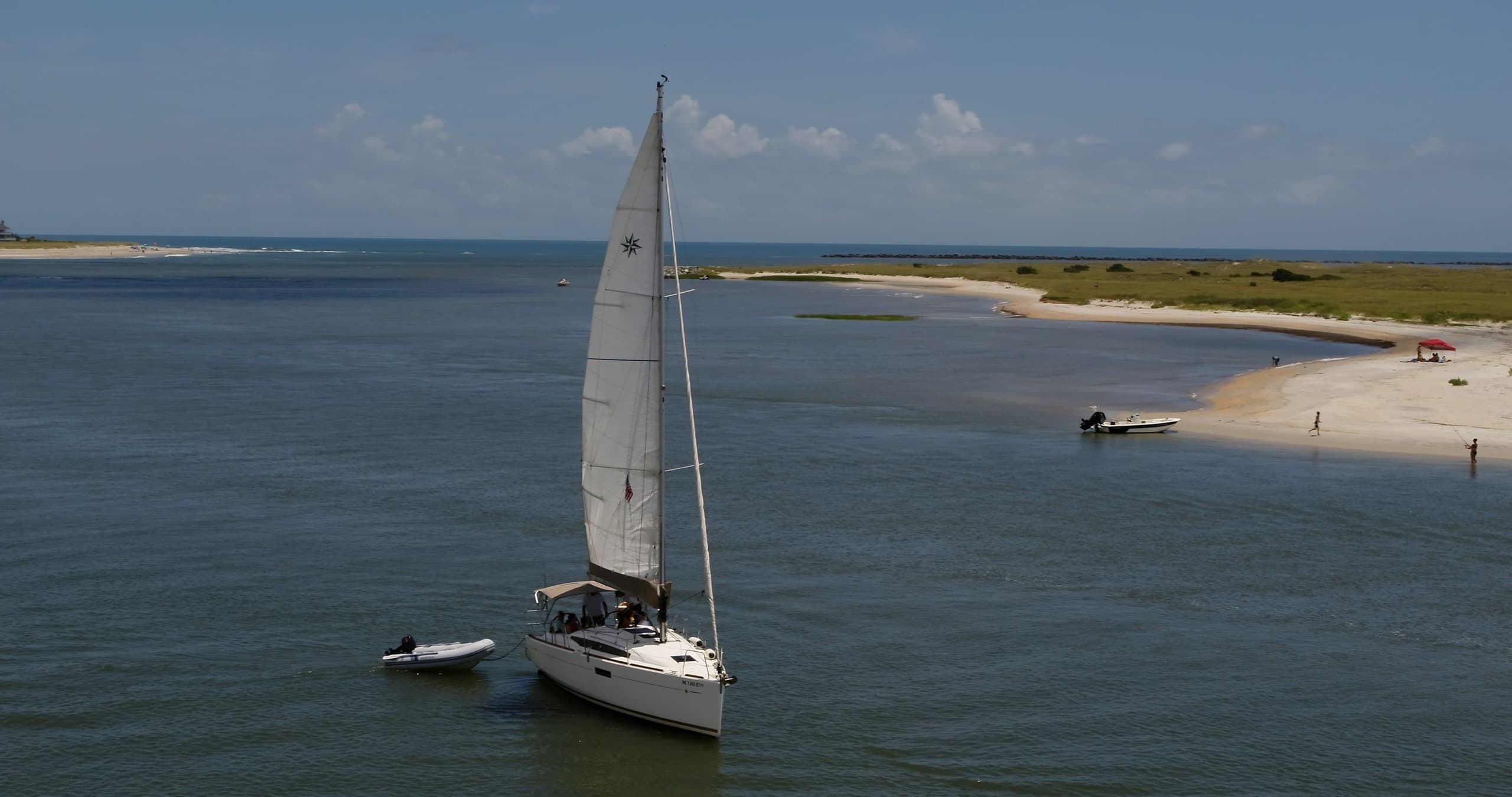 Sailboat cruising along coastal inlet at sunset, scenic seascape