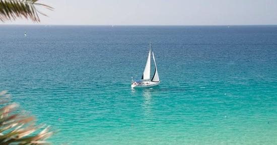 Single sailboat cruising turquoise sea near tropical shoreline
