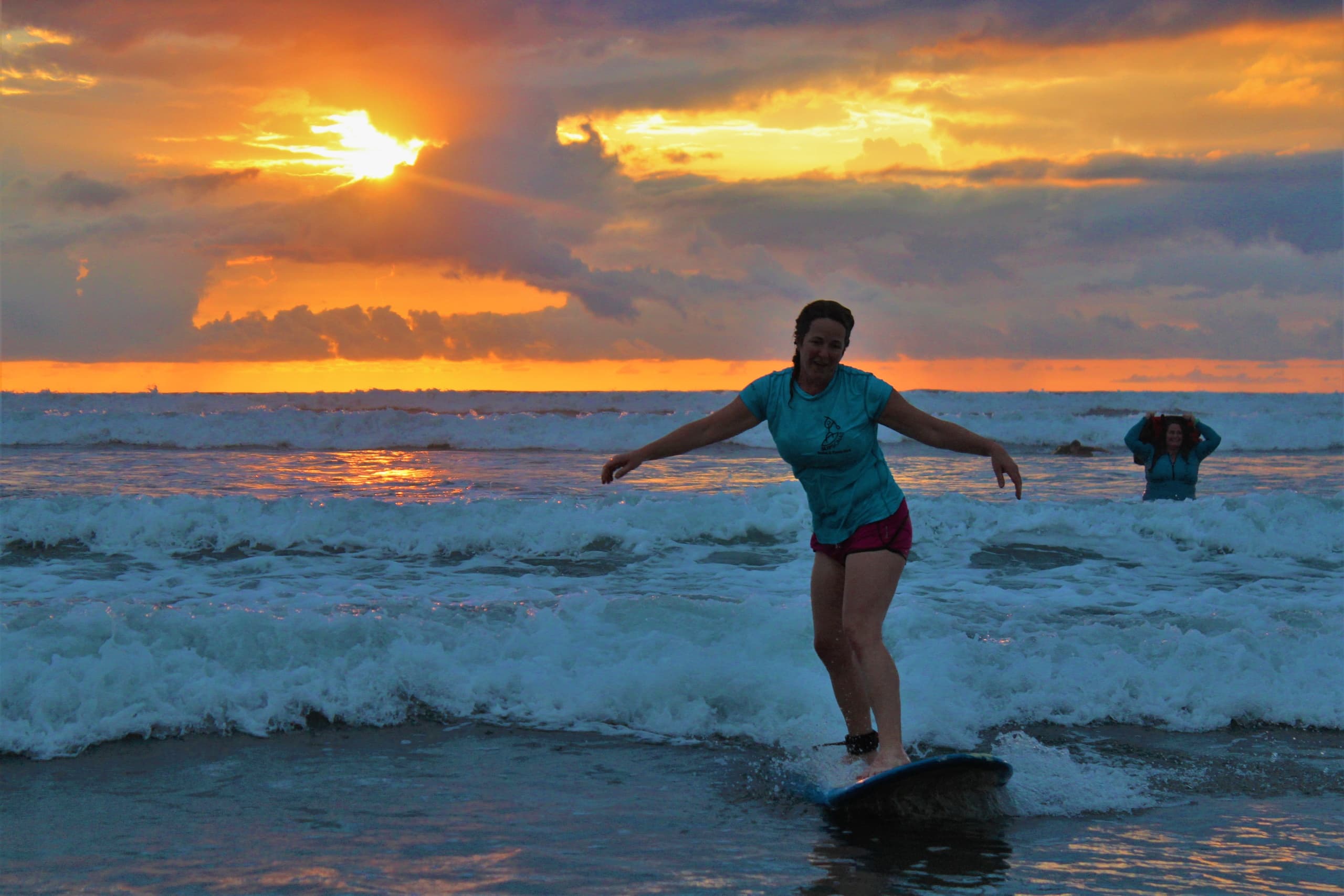Surfer riding ocean waves at sunset on sandy shore