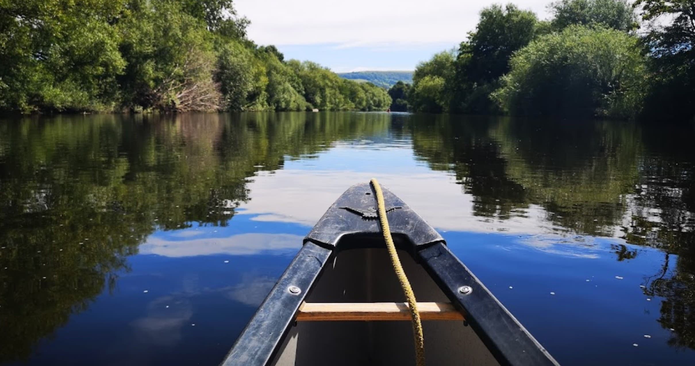 Canoe bow perspective on calm river, paddling adventure experience