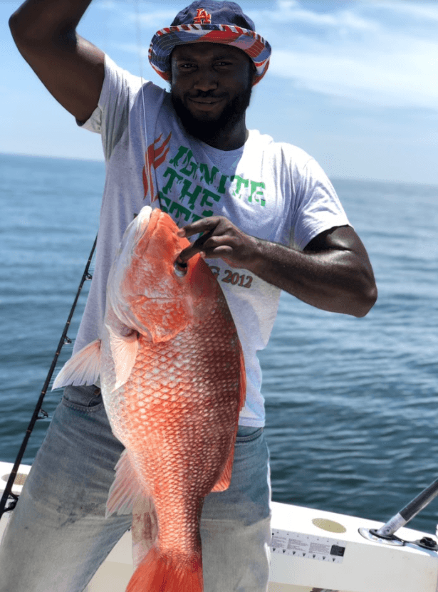 Angler holding large red snapper aboard offshore fishing boat