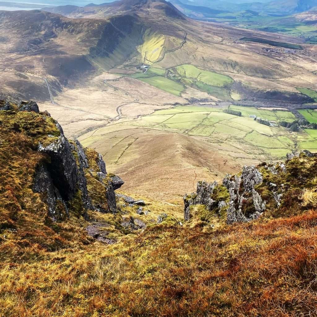 Aerial ridge walk above green valley showcasing rugged terrain
