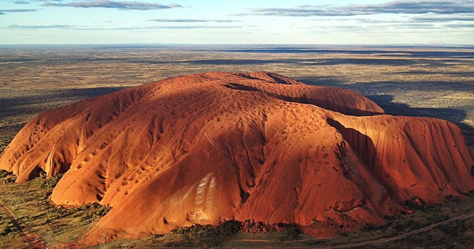 Aerial view of Uluru rock formation glowing in warm light