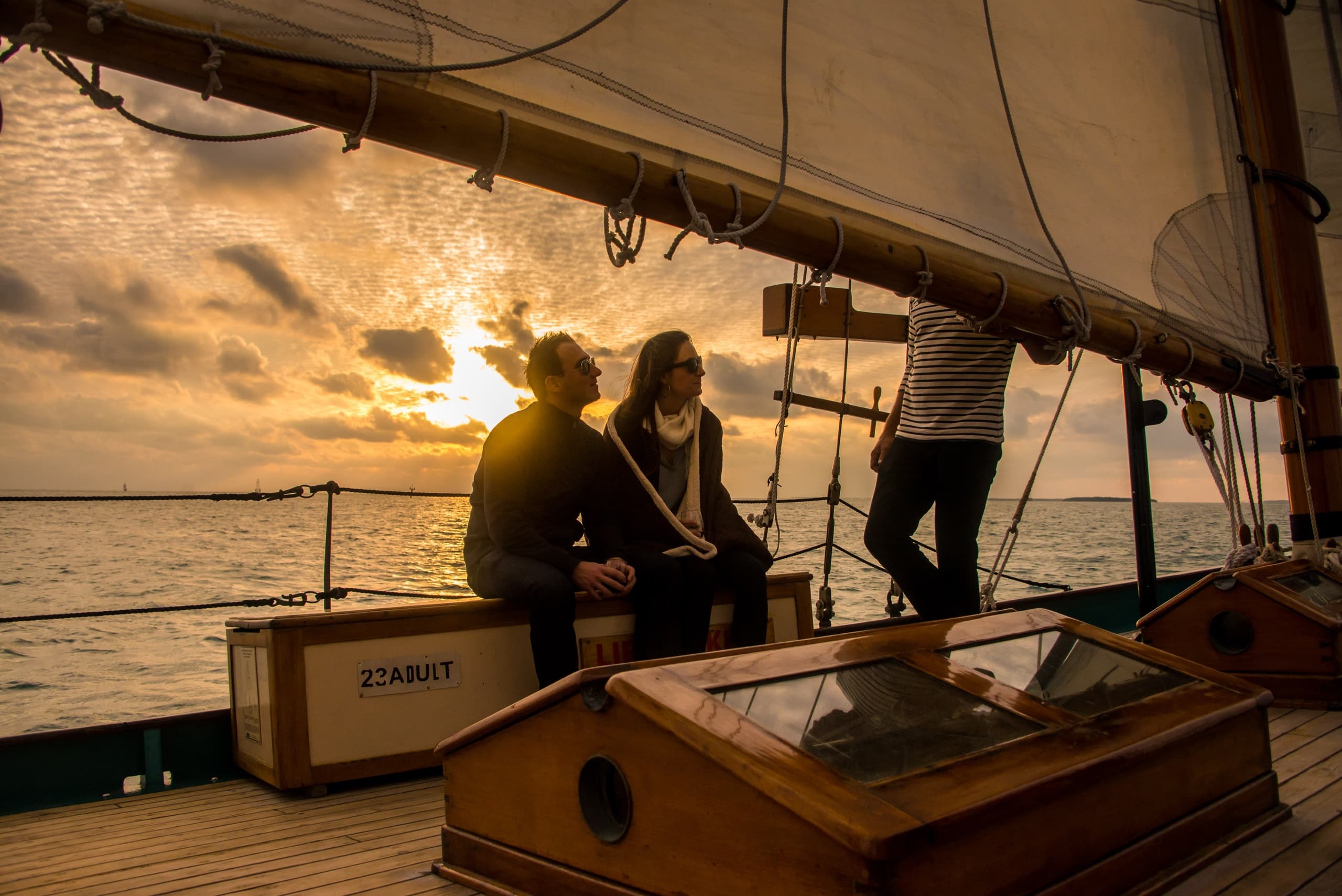 Crew and guests on schooner deck at golden hour sunset