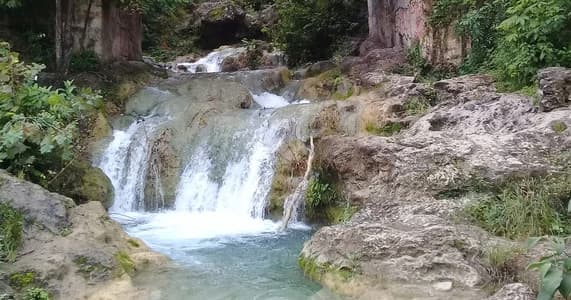 Hikers beside cascading waterfall in lush canyon, Mexico