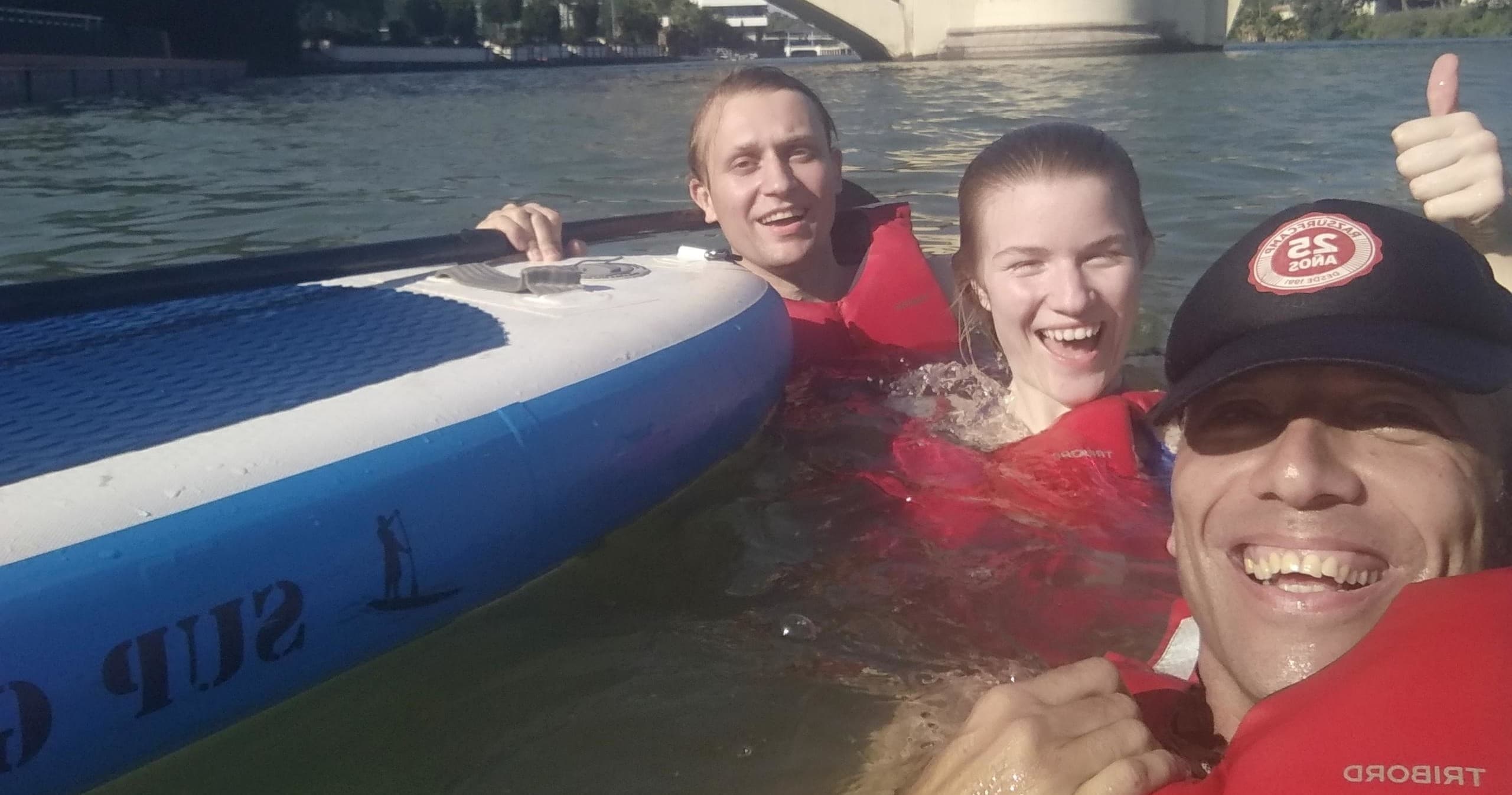 Smiling group in water holding SUP board during Guadalquivir float