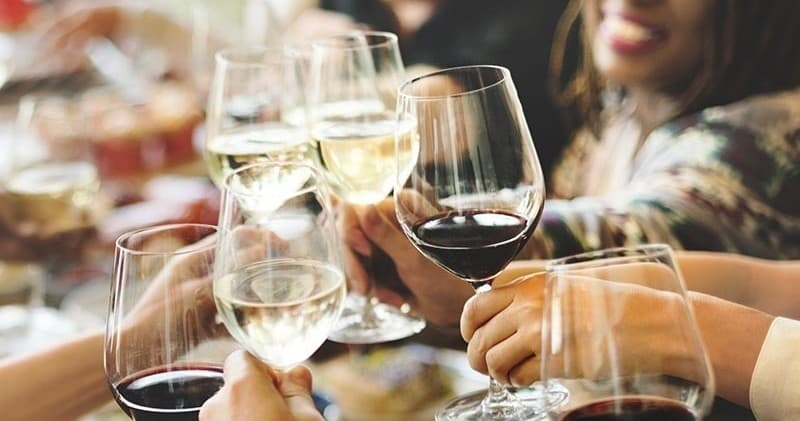 Group cheers with red and white wine glasses at tasting event