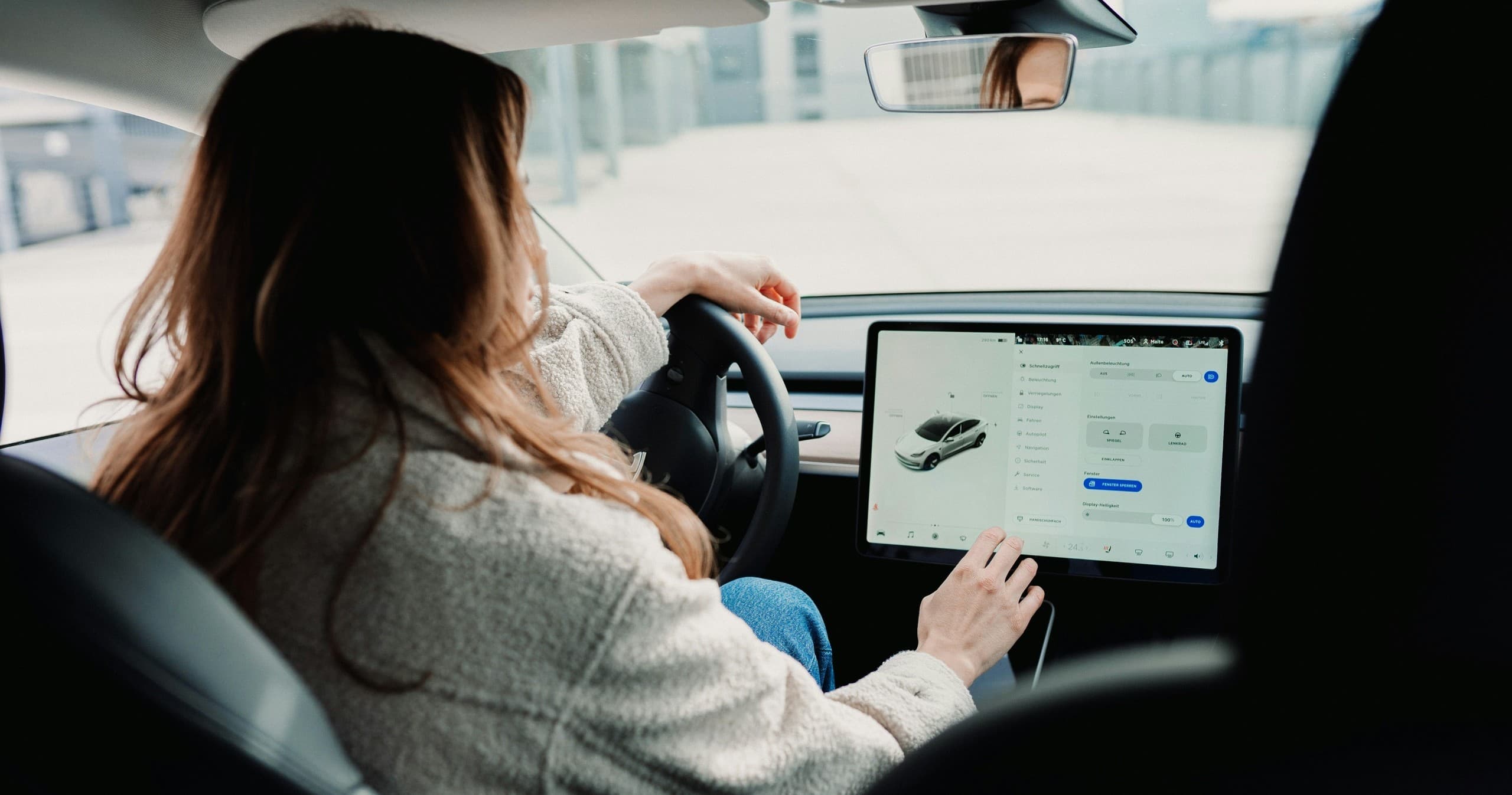 Driver using electric car touchscreen in urban parking lot