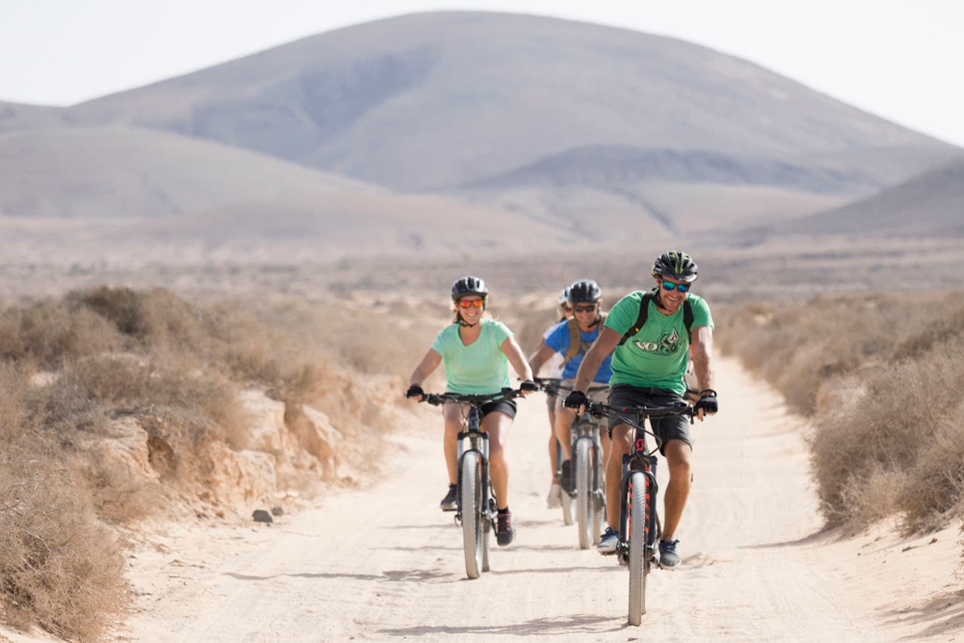 Group mountain bikers riding desert trail toward distant hills