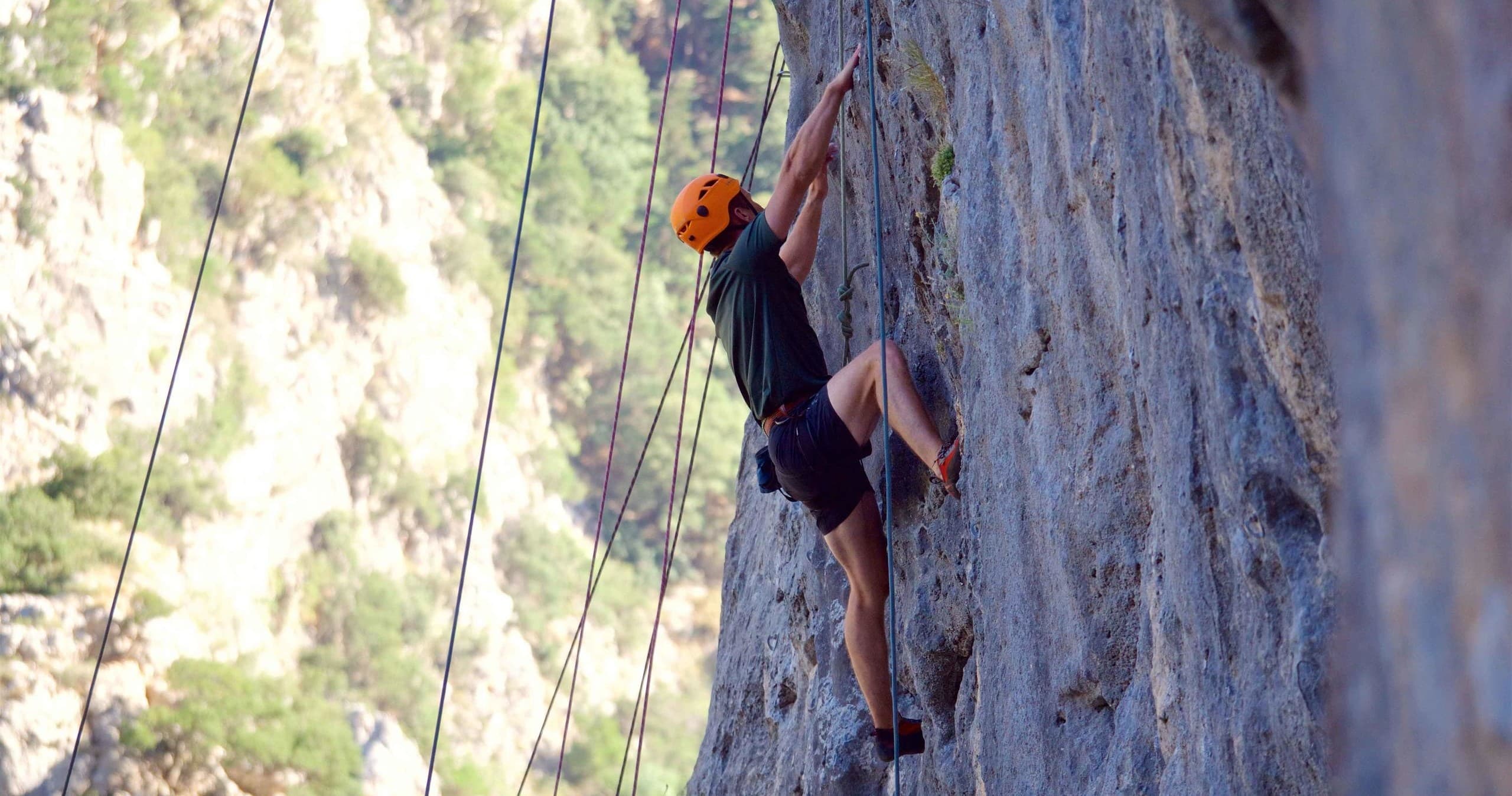 Rock climber ascending steep limestone face on guided outdoor climb