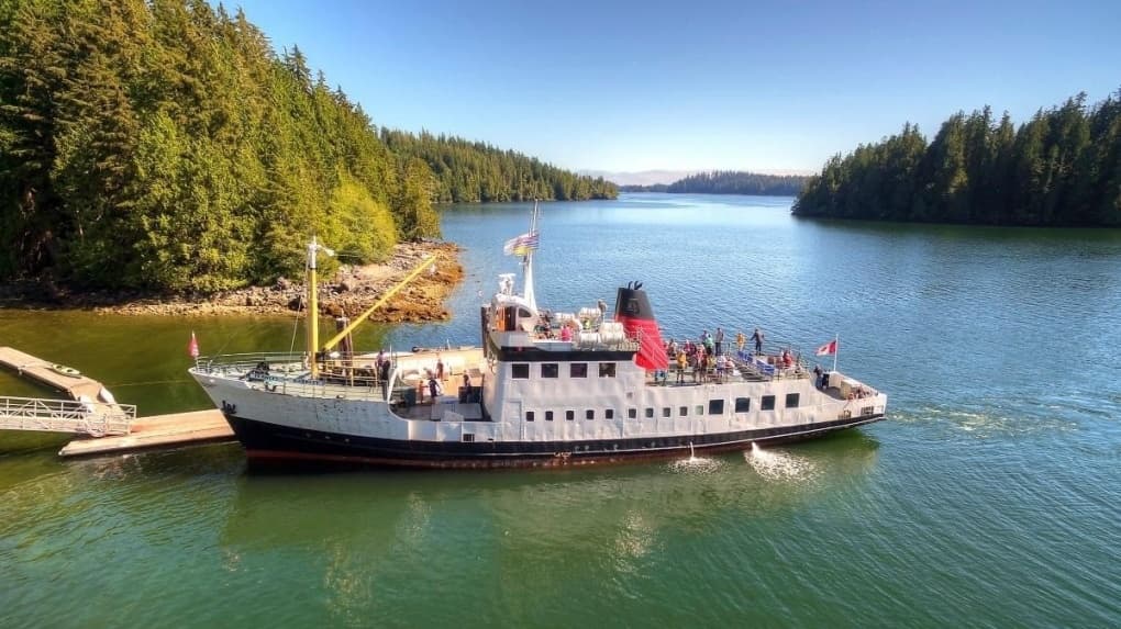 Tour boat anchored in forested bay, passenger wildlife cruise