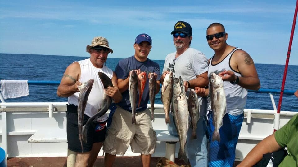 Group of anglers holding mixed catch aboard deep-sea fishing charter