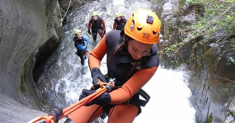 Rappelling down a narrow waterfall canyon during canyoning trip