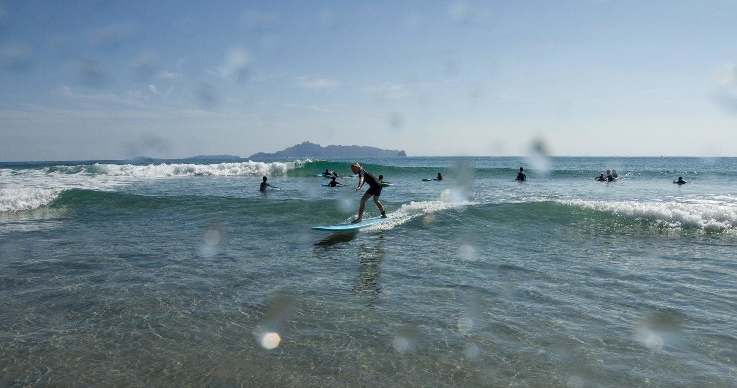 Surfer riding a small wave at Mangawhai Heads ocean beach