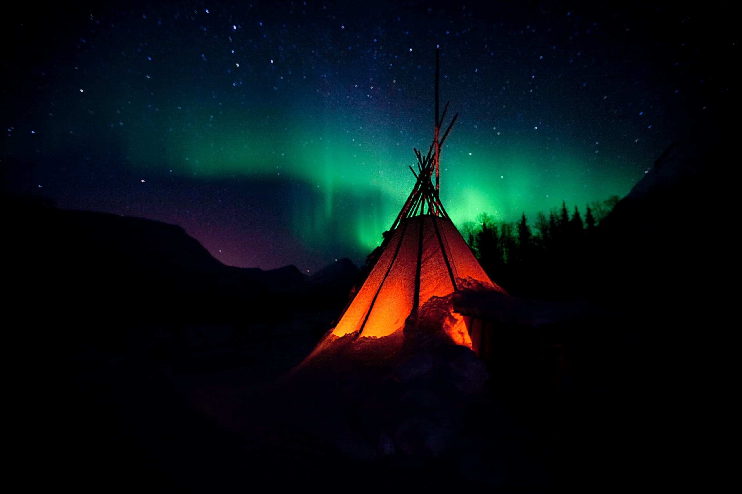 Tented campsite glowing under northern lights in arctic night