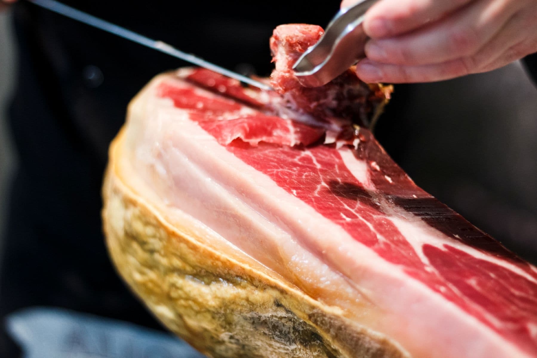Serrano ham being sliced for tapas in Granada market
