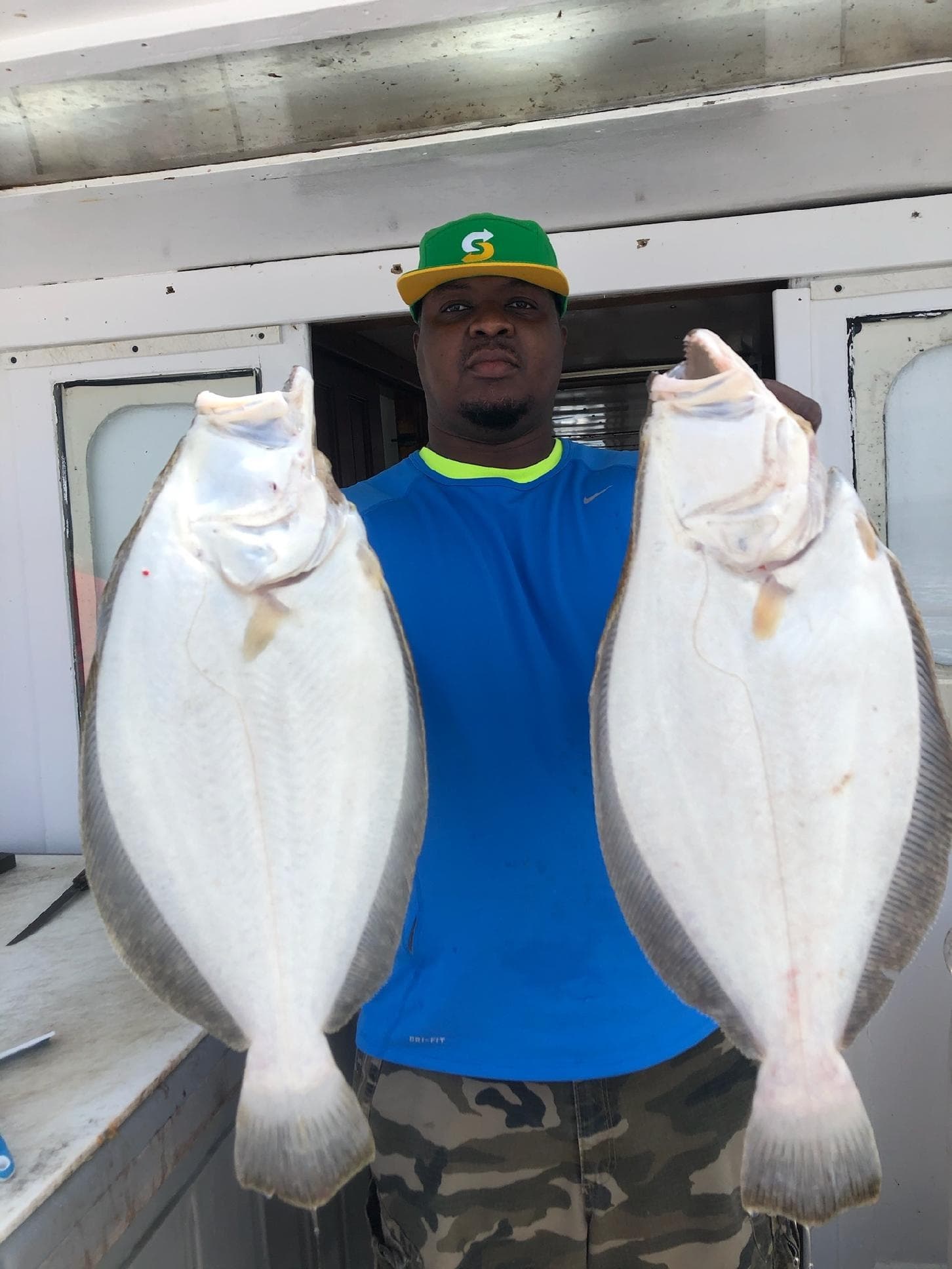 Angler displaying two large flatfish aboard charter boat after catch