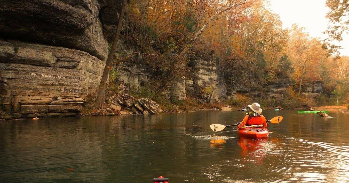 Kayaker paddling through autumn canyon river landscape
