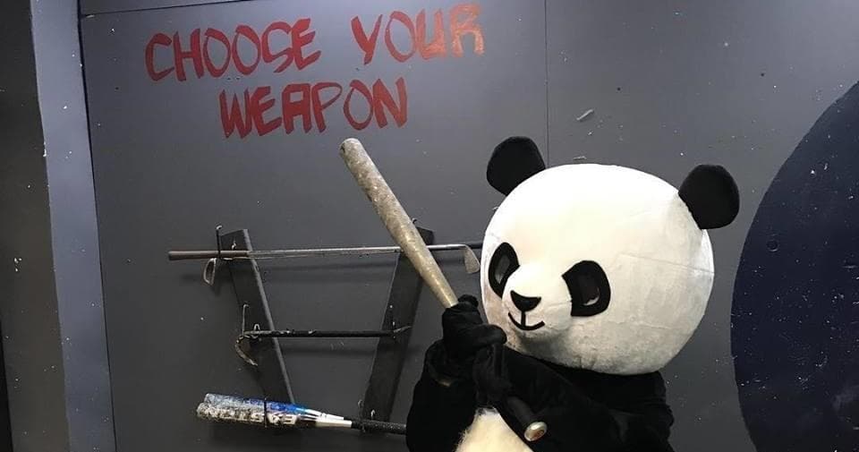 Person in panda costume wielding bat in themed indoor smash room
