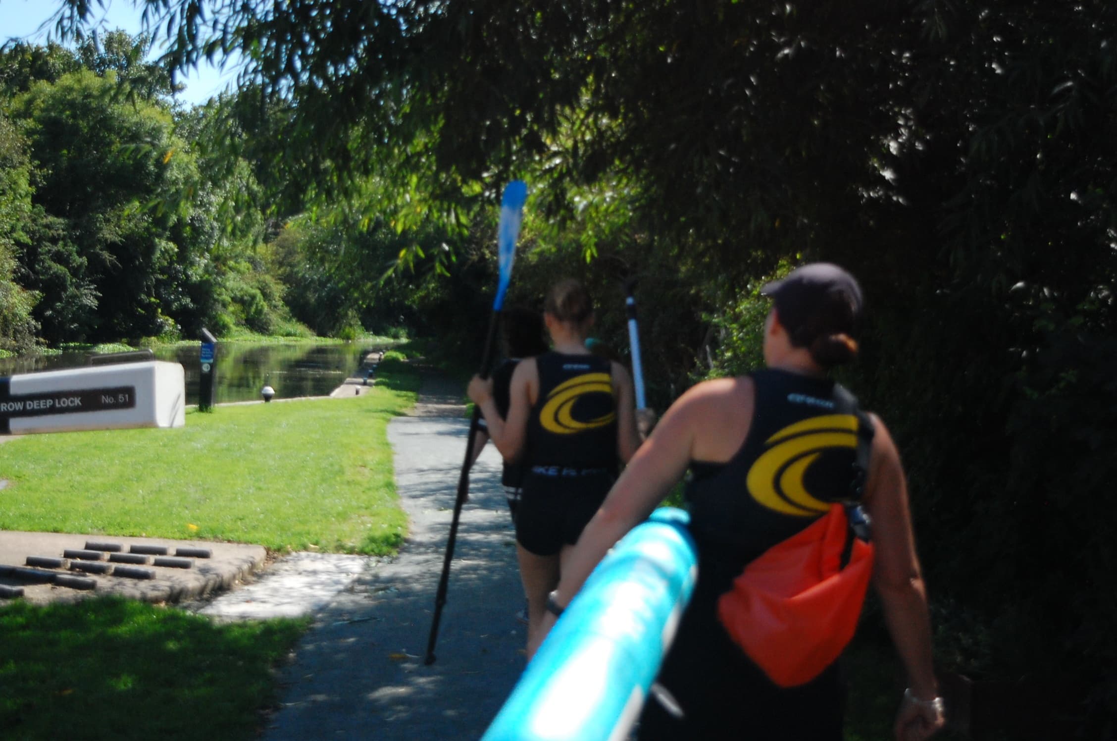 Paddlers carrying kayaks along riverside trail toward launch