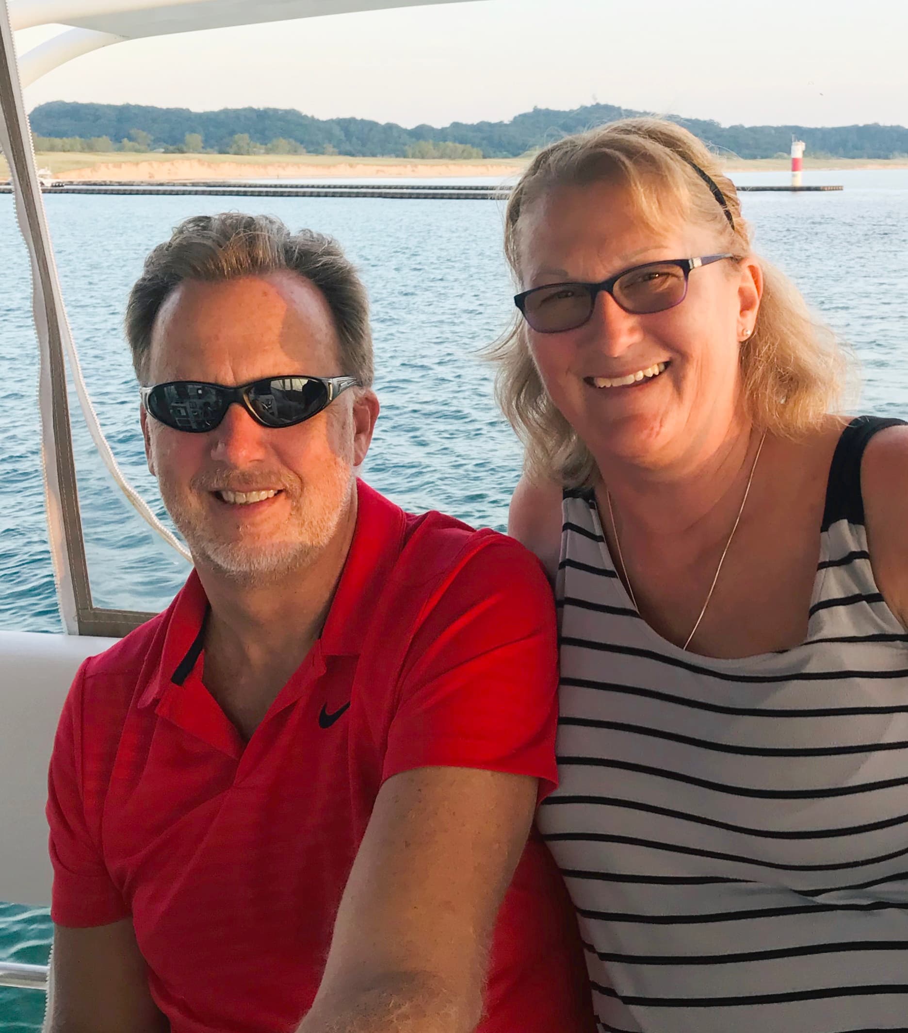 Smiling couple aboard boat near shoreline enjoying sunset cruise