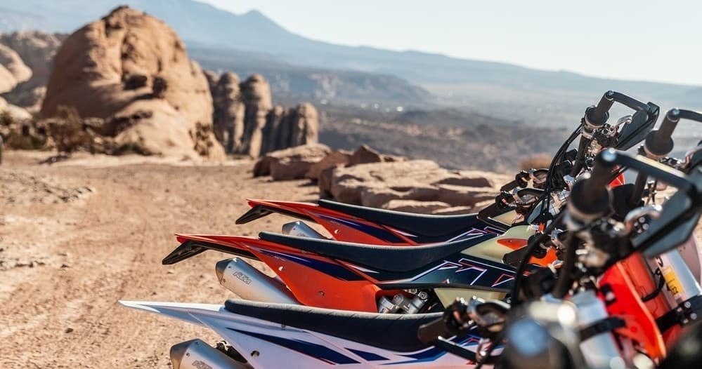 Close-up row of dirt bikes at Moab trailhead, scenic desert