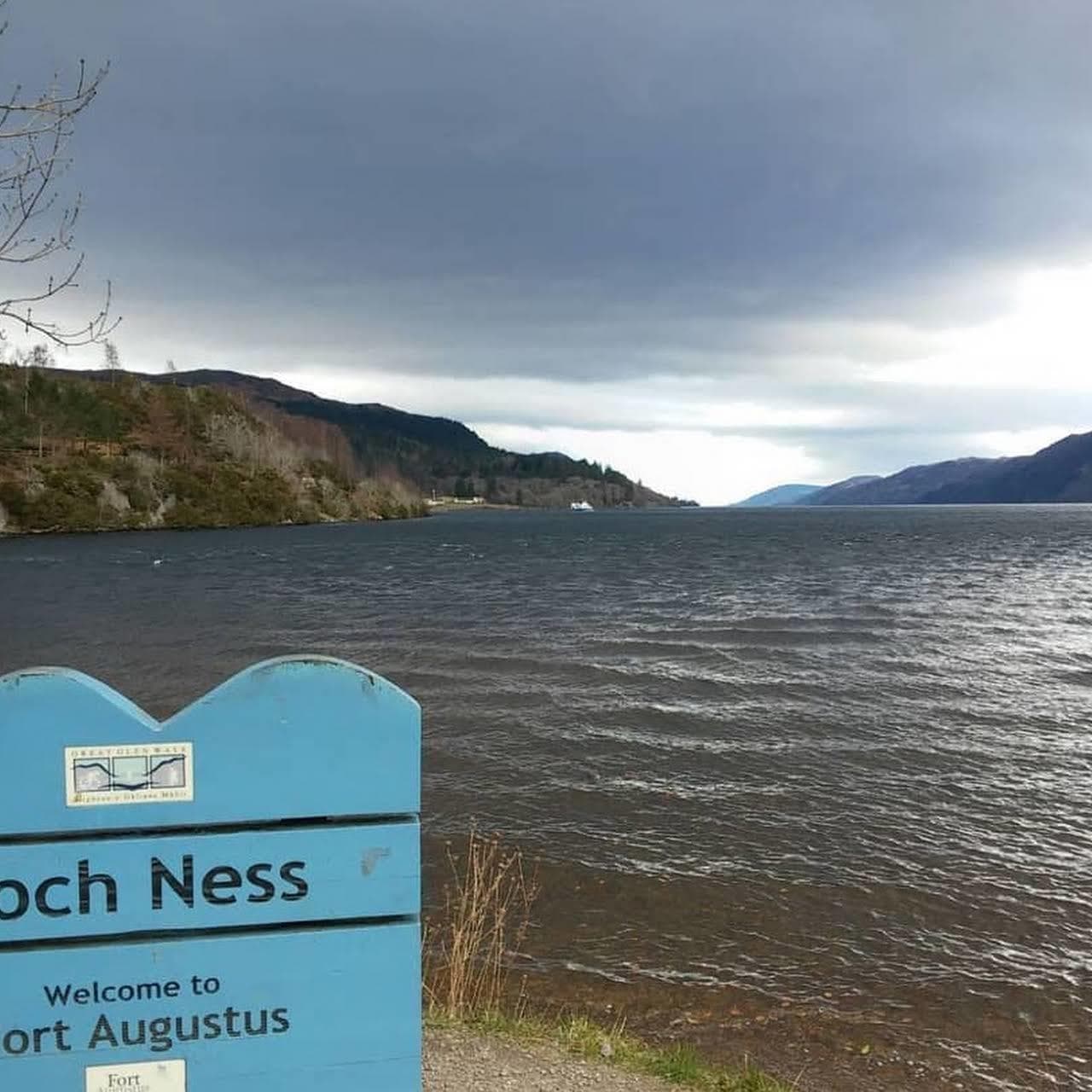 Loch Ness shoreline view with welcome sign and cloudy skies
