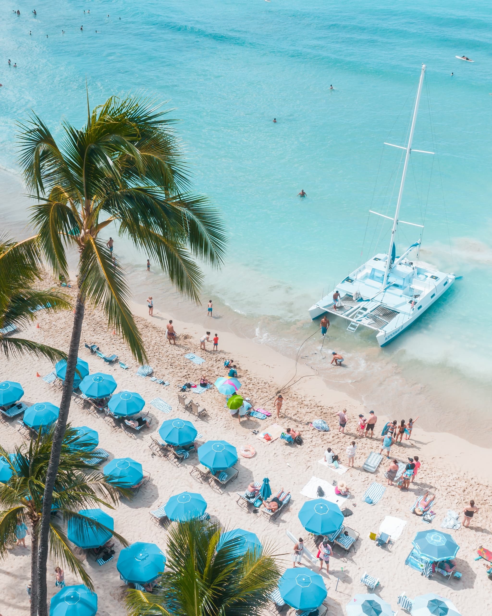 Aerial view of turquoise beach with catamaran and umbrellas