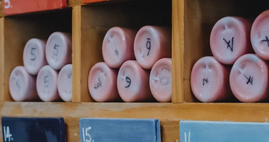 Close-up pastel paint rollers stored in wooden cubbies at studio