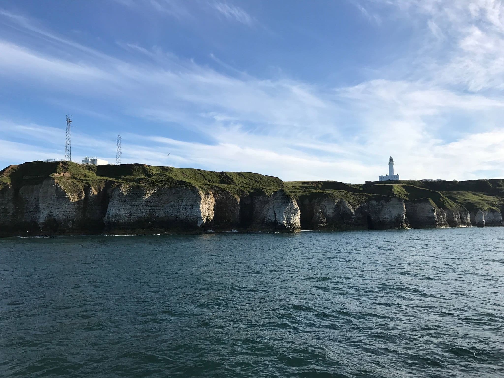 Harbor cruise approaching lighthouse on rugged Yorkshire cliffs