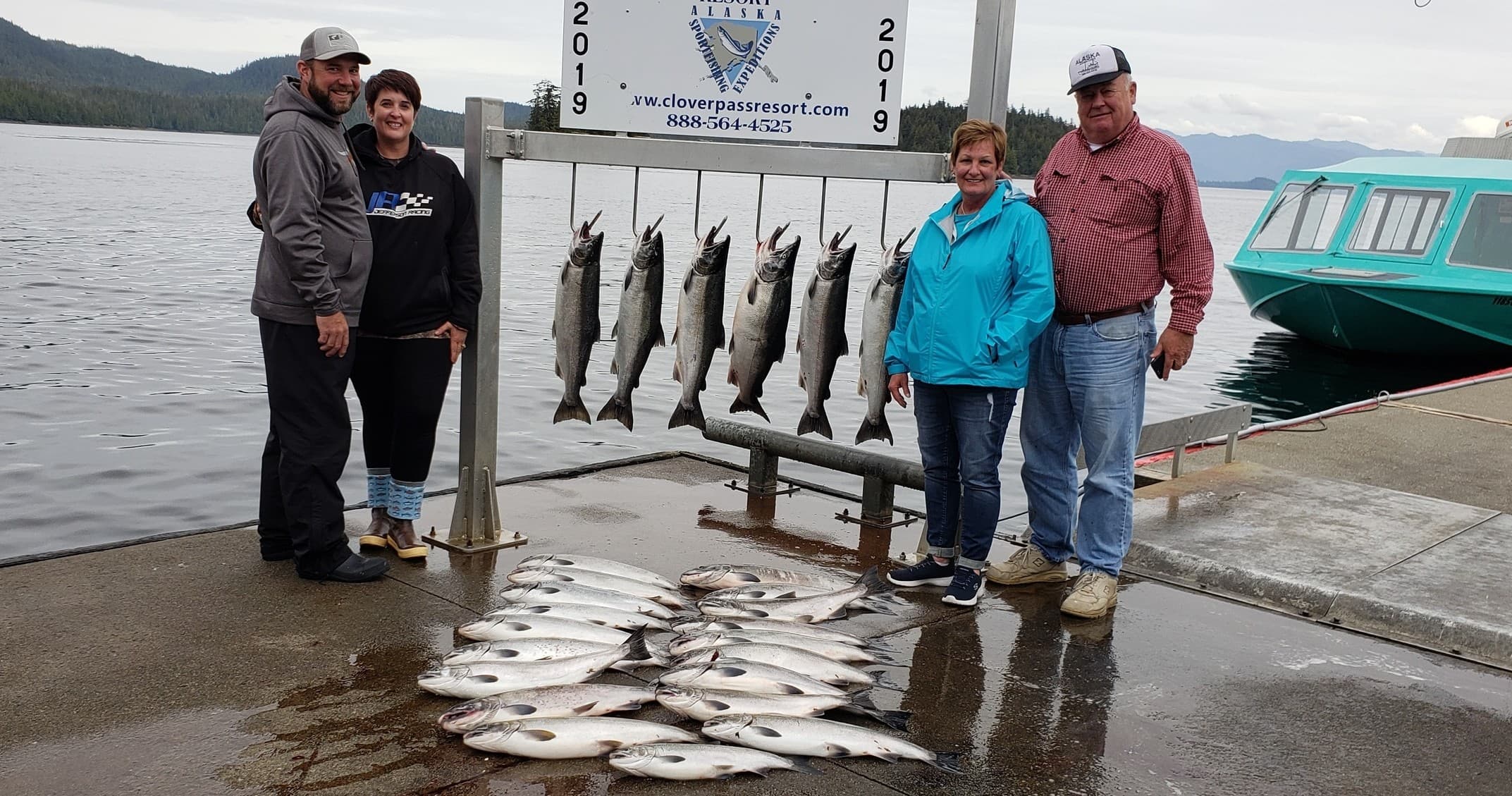Family and guide with mixed salmon catch displayed on dock
