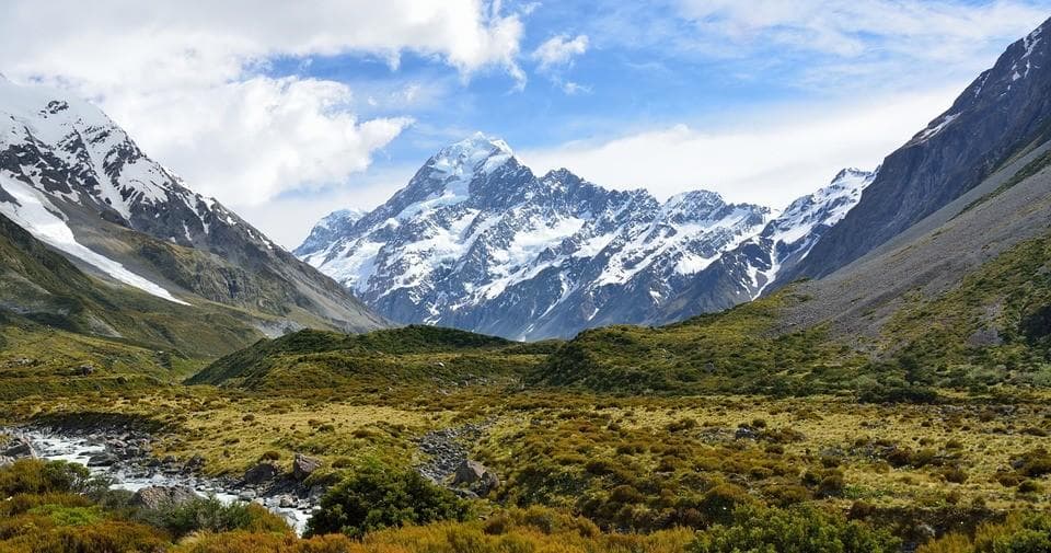 Hikers in alpine valley with snow-capped peaks, scenic backcountry trek