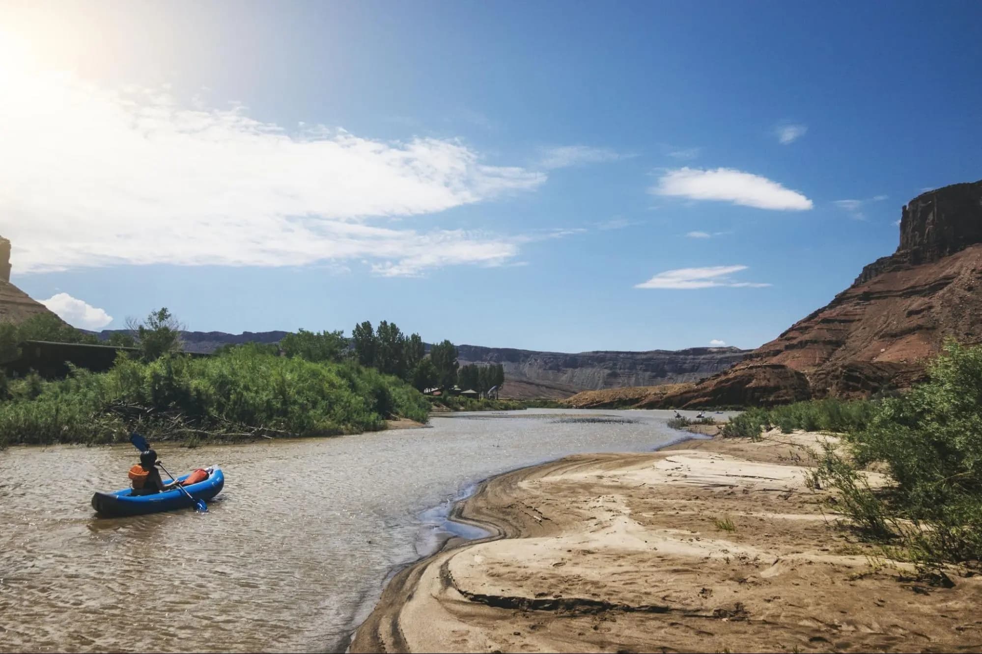 Solo kayaker navigating calm river amid rugged canyon landscape