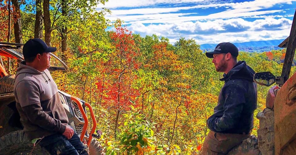 UTV riders overlooking colorful mountain valley and scenic fall overlook