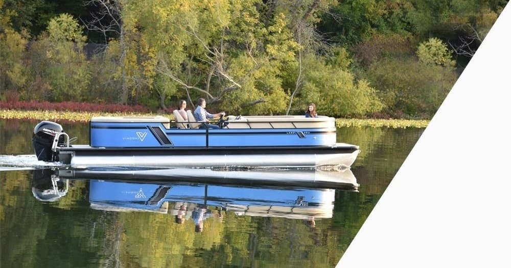 Small pontoon cruising with lake reflection on calm forested shore