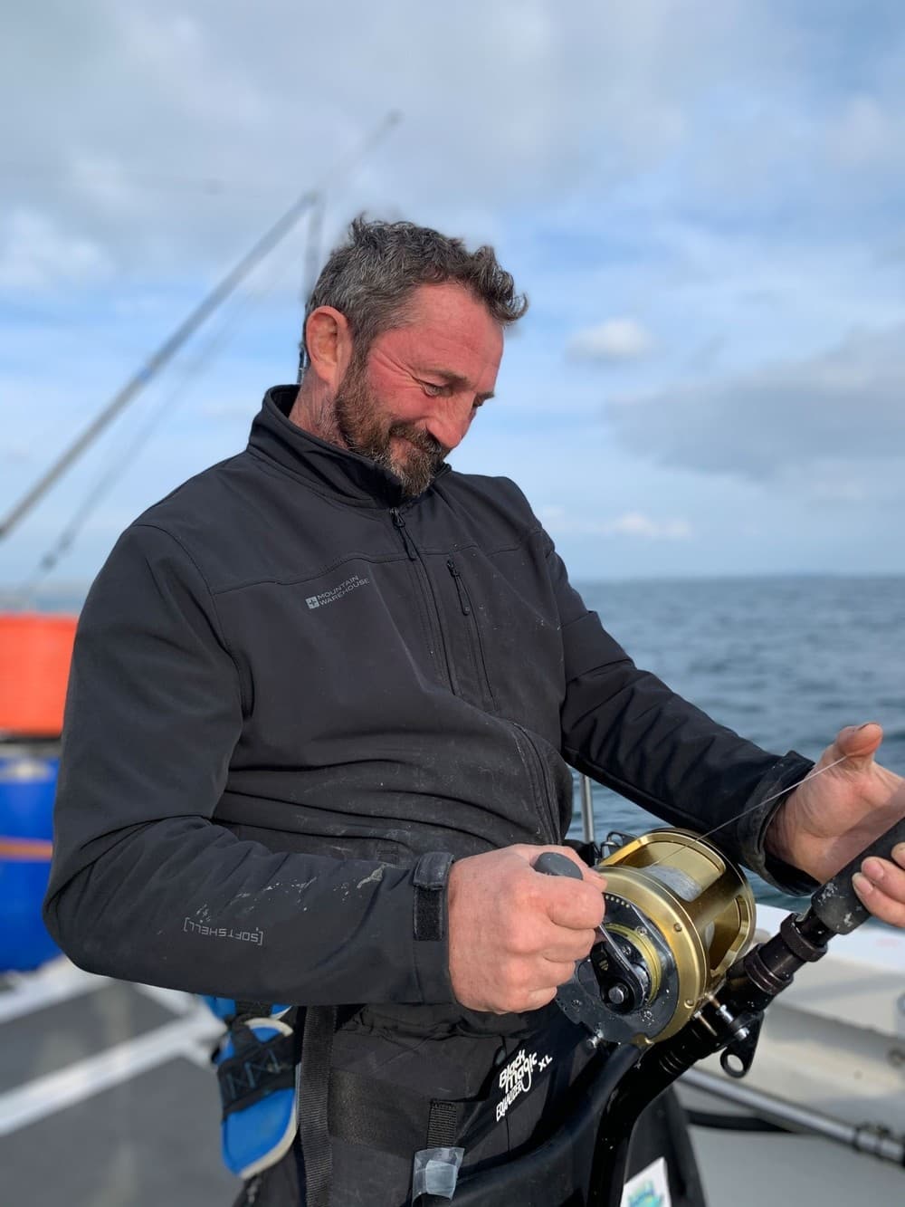 Angler reeling heavy tackle on offshore charter with sea backdrop