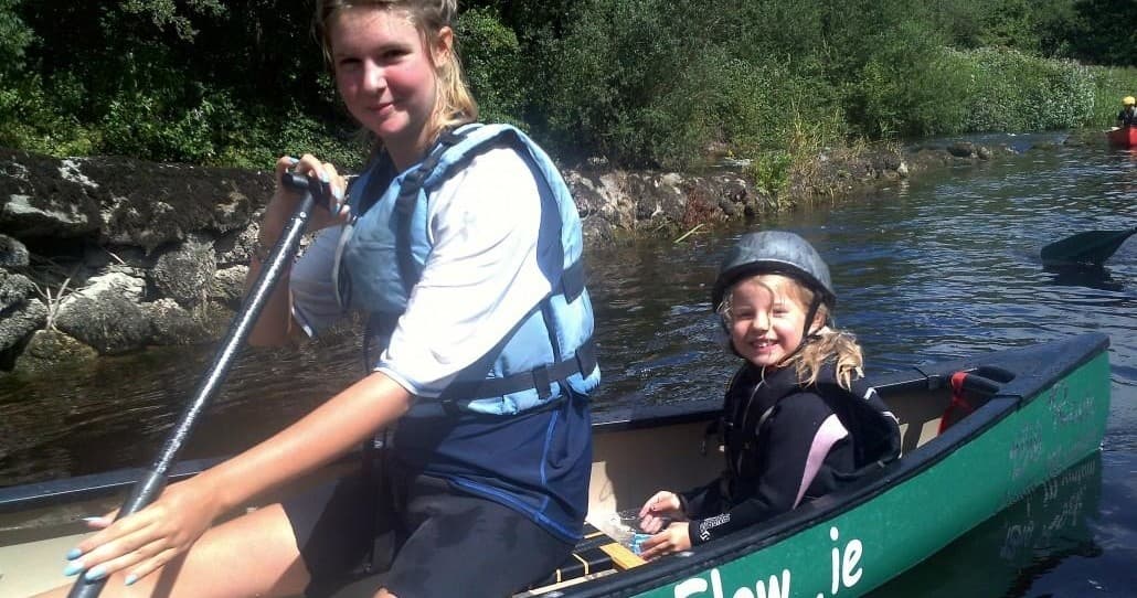 Adult and child canoeing on a shallow river, family outdoor adventure