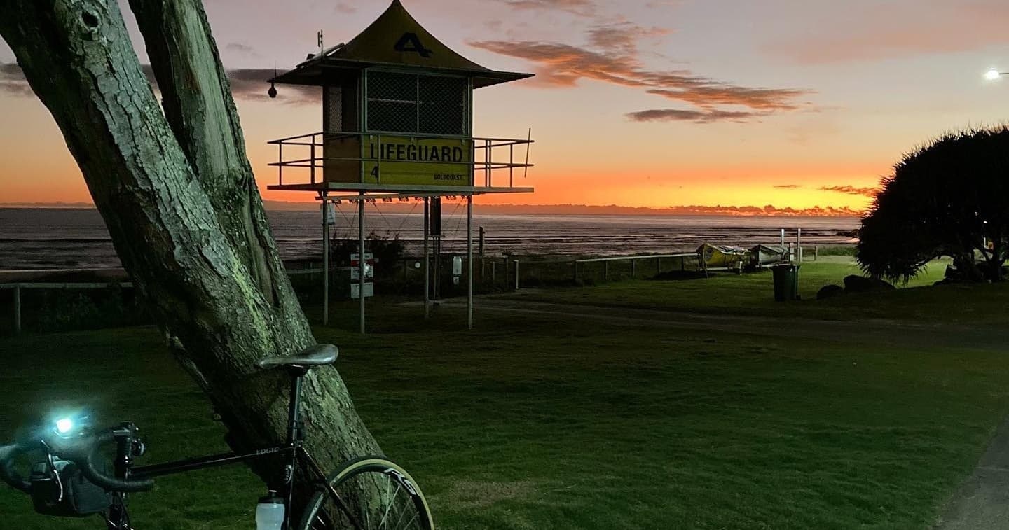 Bicycle leaning near lifeguard tower at coastal sunset park