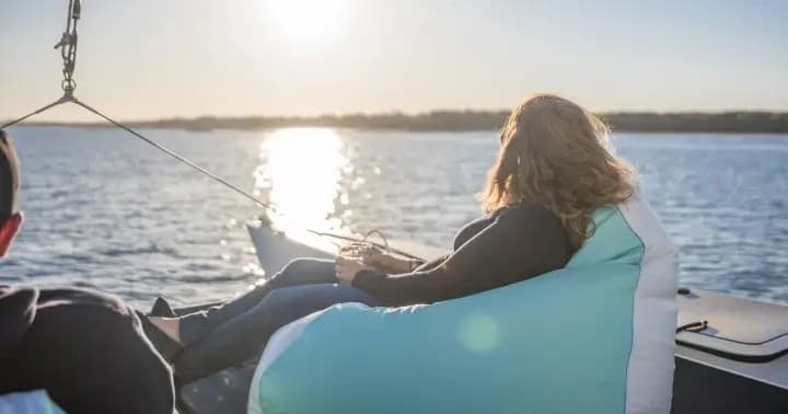 People lounging on sailboat deck enjoying sunset coastal cruise