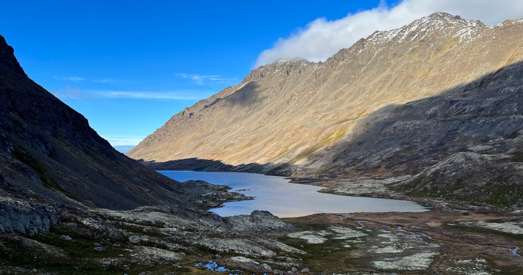 Wide alpine lake valley under blue sky, scenic backcountry hike