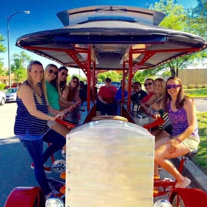 Friends pedaling beer bike through sunny Birmingham neighborhood park