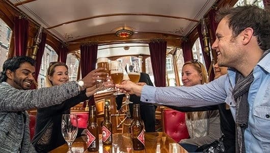 Friends toasting on an Amsterdam canal boat tour inside cabin