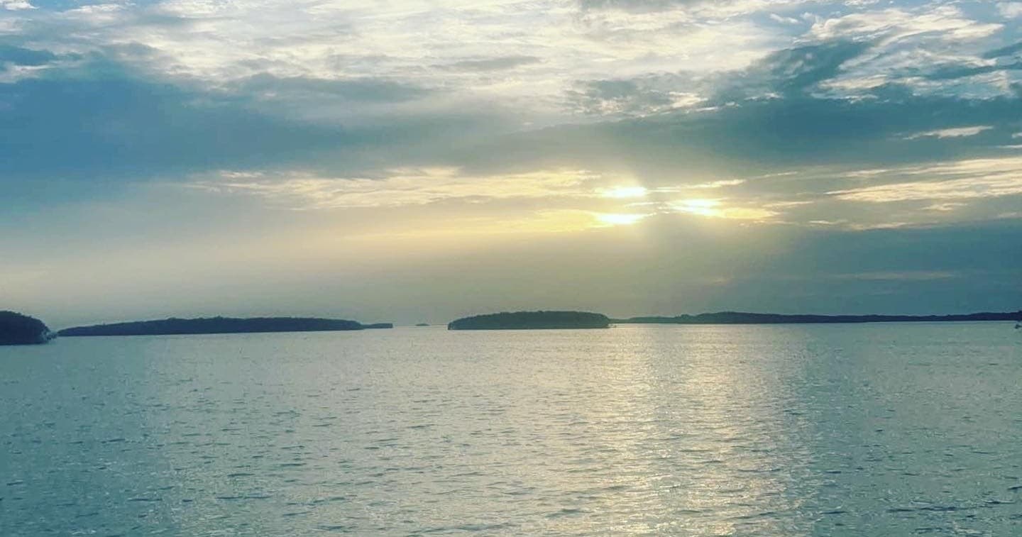 Calm sunrise over open sea with distant islands and horizon