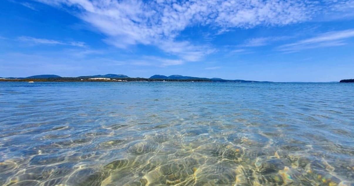 Clear shallow bay with sandy bottom and distant island view