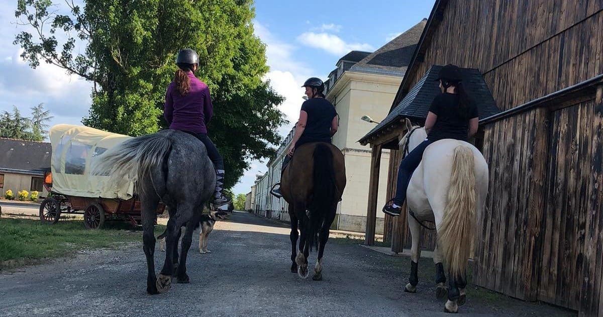Group of three riders on country road leaving the stable