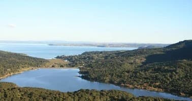 Viewing coastal lake and ocean vista over rolling NZ hills