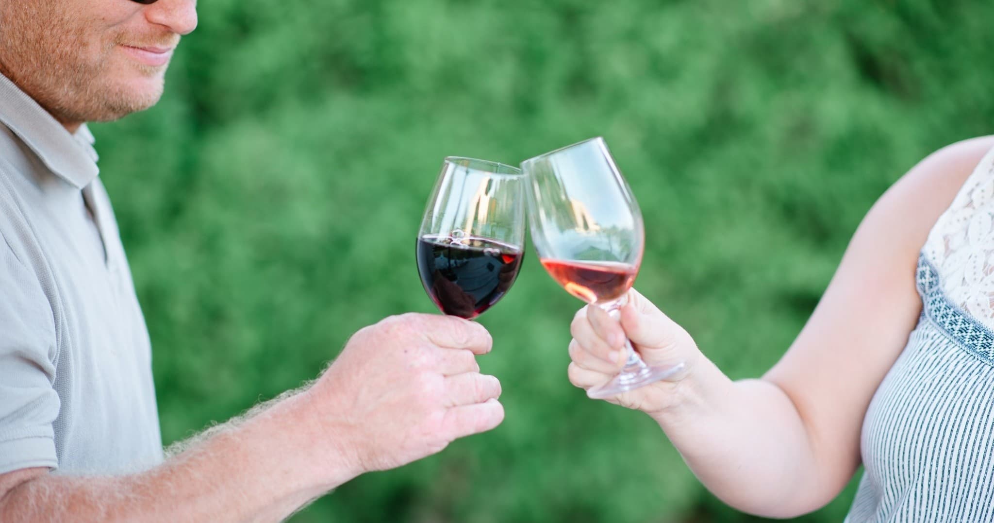 Couple toasting wine outdoors in backyard vineyard tasting