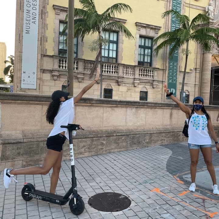 People on e-scooters high-fiving near Miami museum