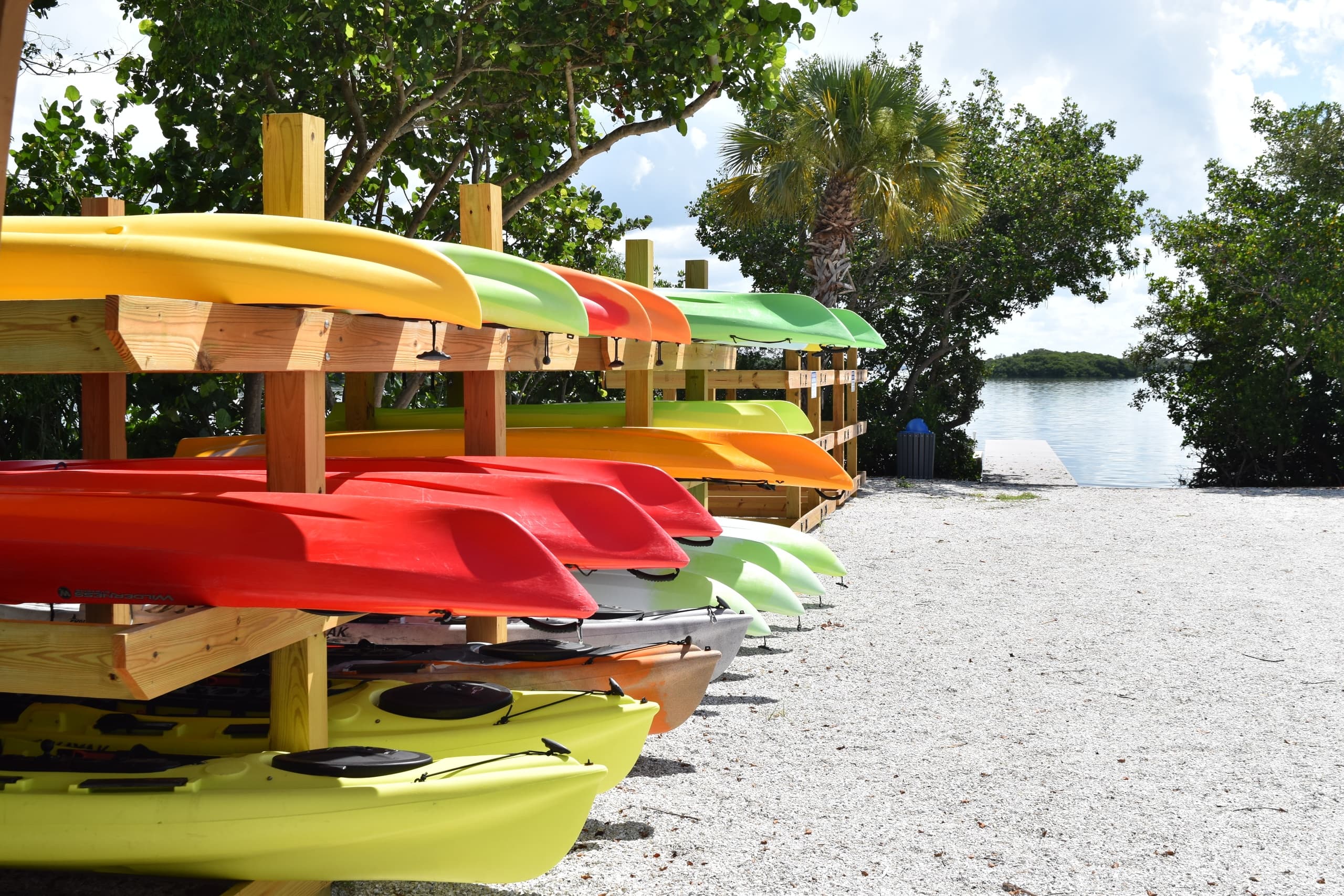 Stacked colorful rental kayaks on sandy shore by a sheltered inlet