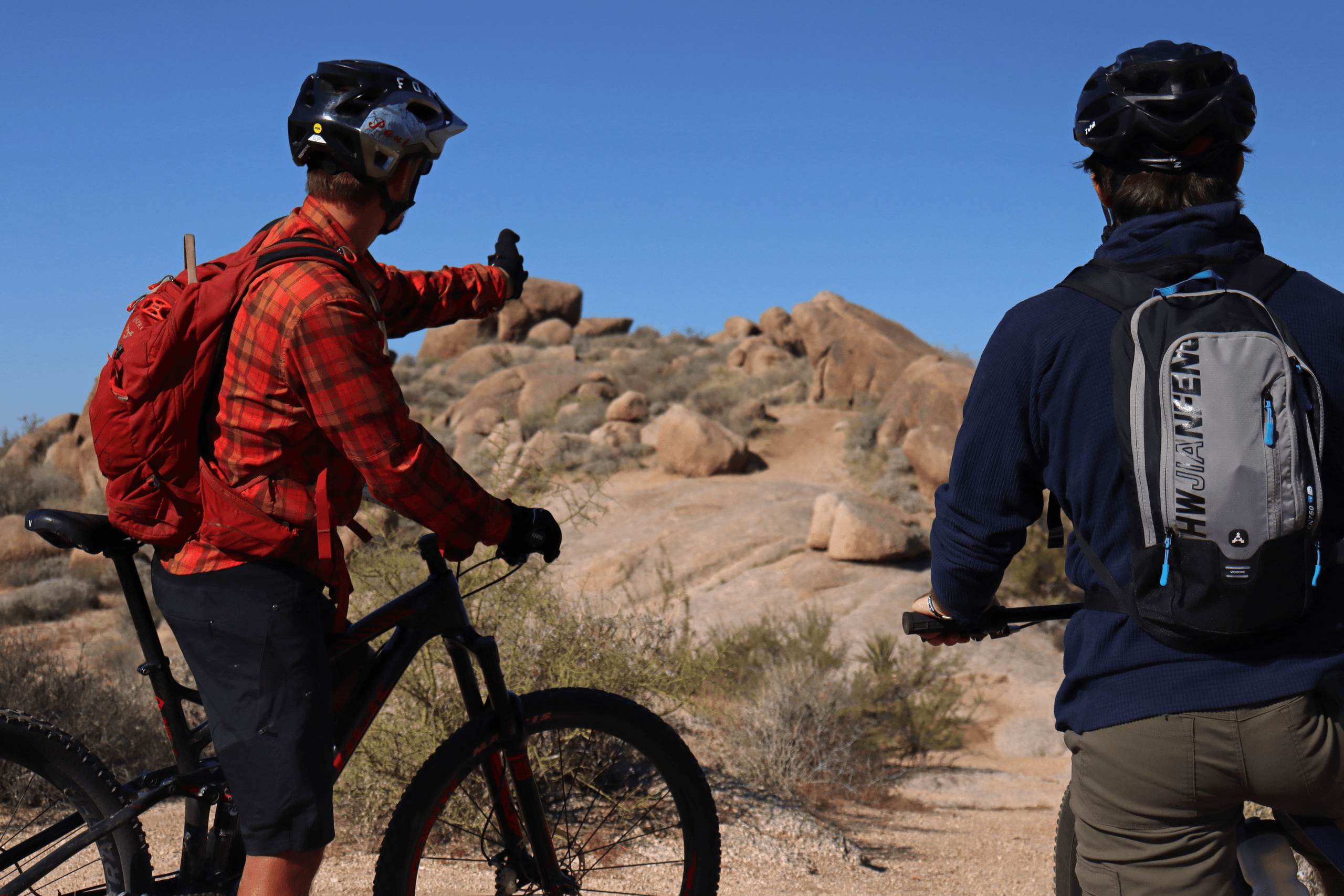 Mountain bikers scouting rocky desert terrain on guided ride